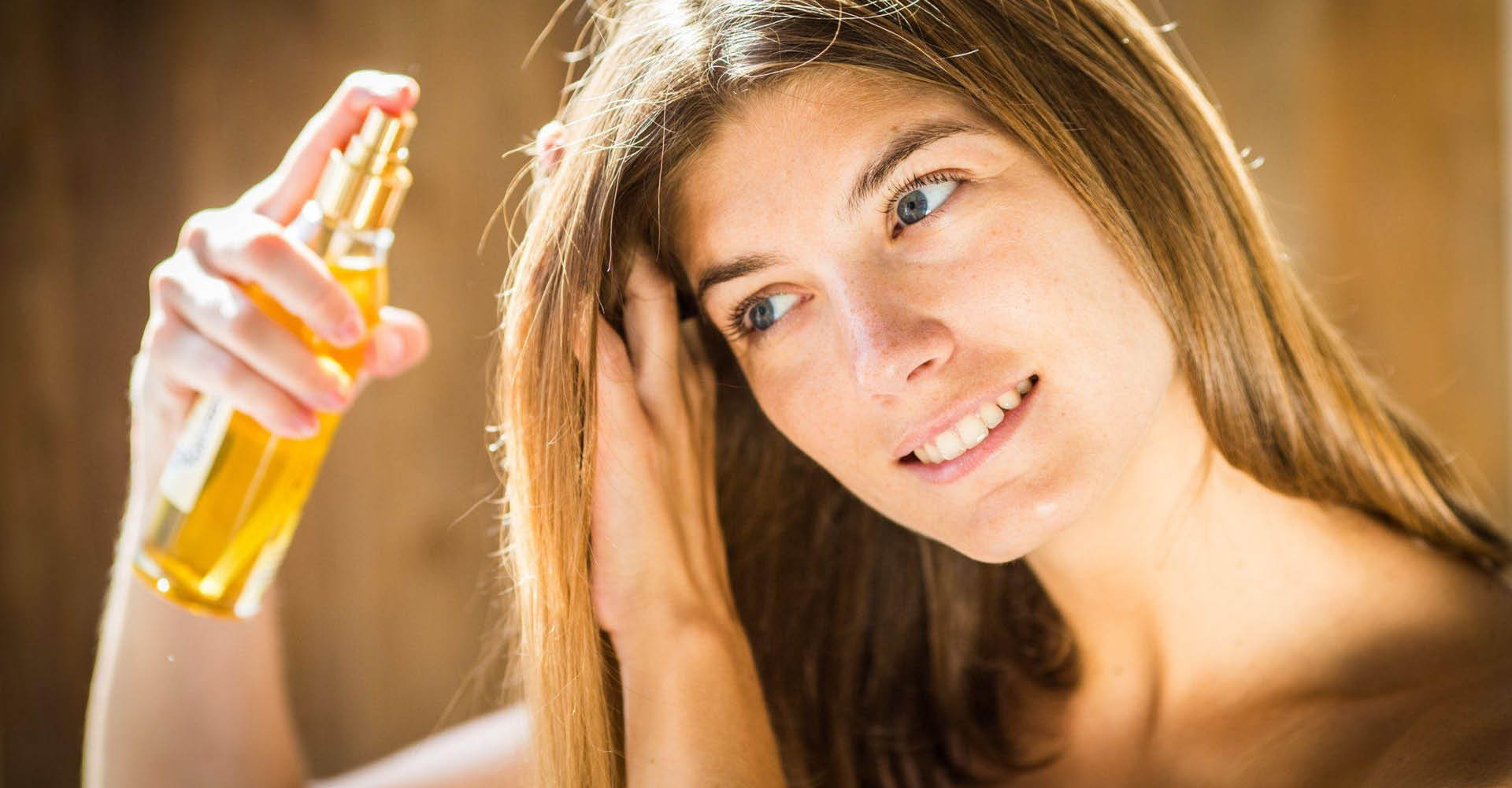 Immagine di una ragazza bionda, che si sta applicando uno spray sui capelli